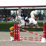 Caruschka's tail flies like a flag in the wind as she carries Eduardo Menezes over a jump.